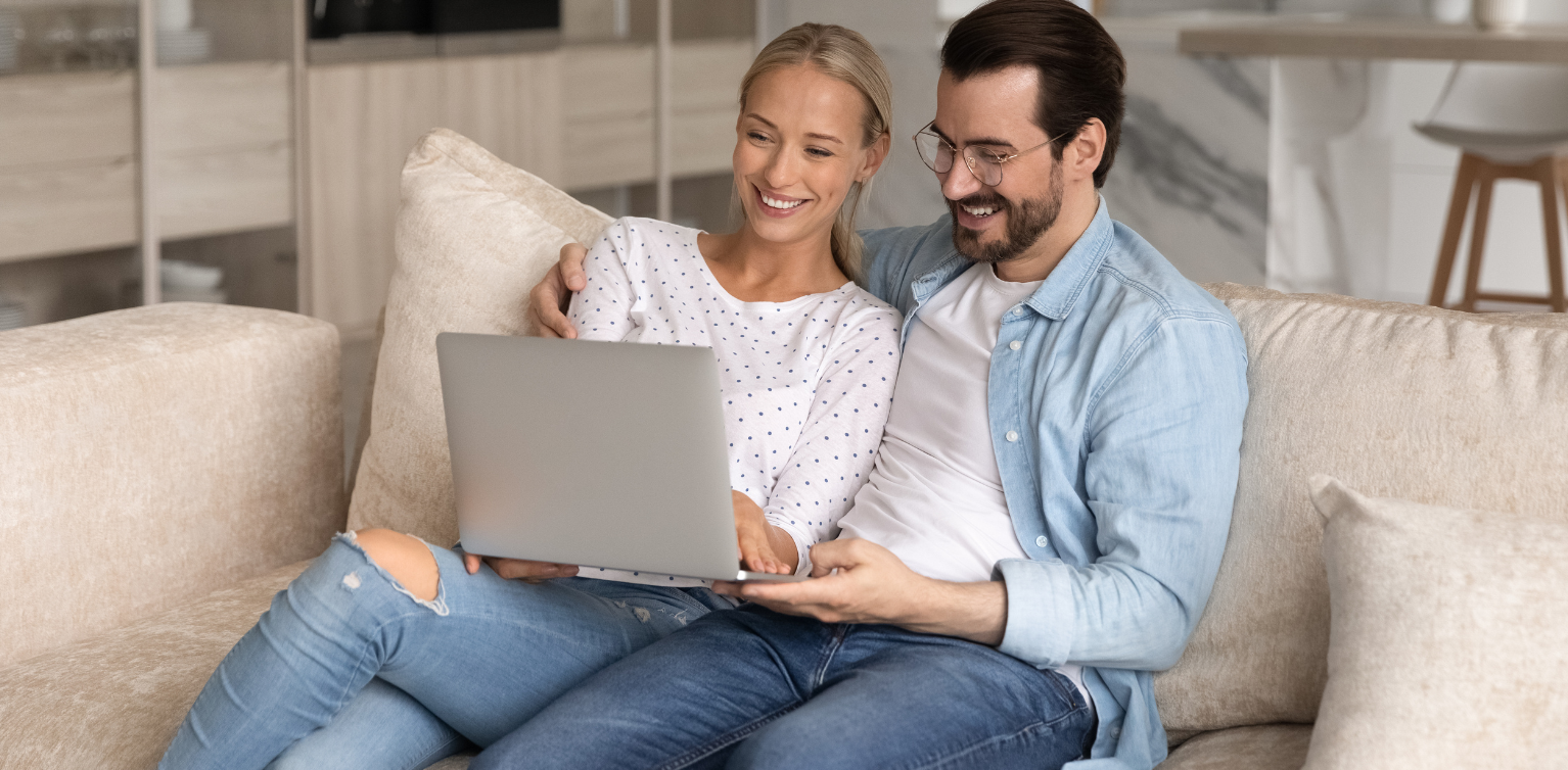 man and woman on couch looking at laptop